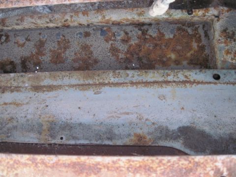 1979 Ford Bronco - Close-up of a heavily rusted metal frame section, likely from an older vehicle.