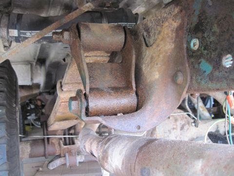 1979 Ford Bronco - Close-up view of a heavily rusted suspension part and exhaust pipe.