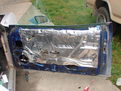 1973 Ford Ranchero - The interior of a blue car door, showing the installation of sound deadening material and exposed wiring.