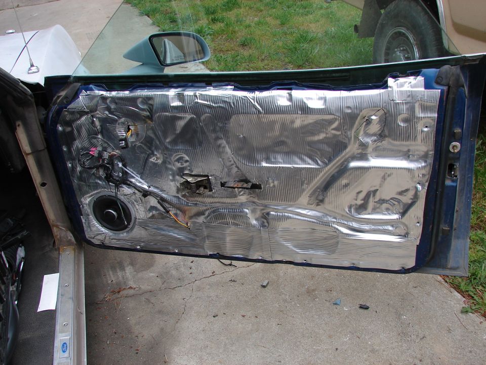 Car door interior panel removed, showing sound deadening material and speaker wiring