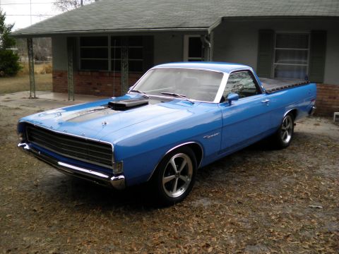 1969 Ford Ranchero - A blue 1969 Ford Ranchero pickup truck is parked in front of a house, a black hood scoop and racing stripes on the hood.