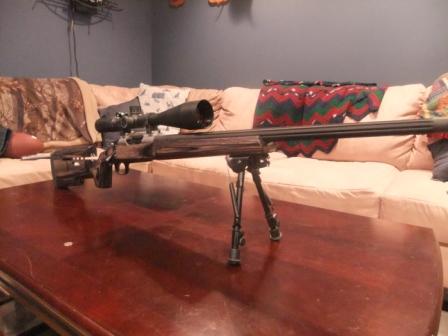 1996 Ford Bronco - A sniper rifle with a scope and bipod is displayed on a wooden table in front of a couch.
