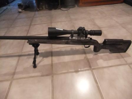 1996 Ford Bronco - A rifle with a scope and bipod is shown resting on a tiled floor, with a website logo visible in the lower right corner.