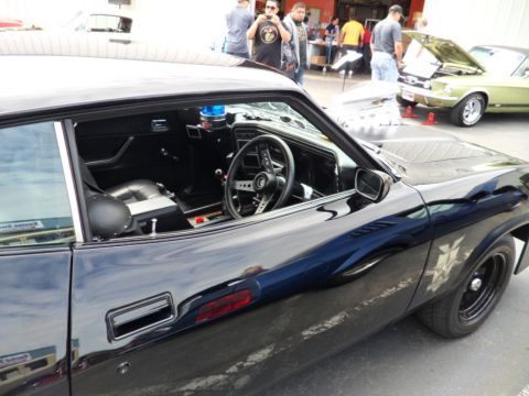 1956 Ford Fairlane - Side view of a black coupe, showing its interior and exterior details. Another vehicle is visible in the background.