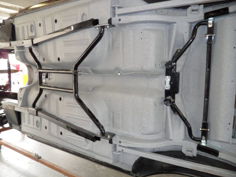 Underside of a car showing frame, suspension components, and sway bars. The chassis appears to be freshly painted