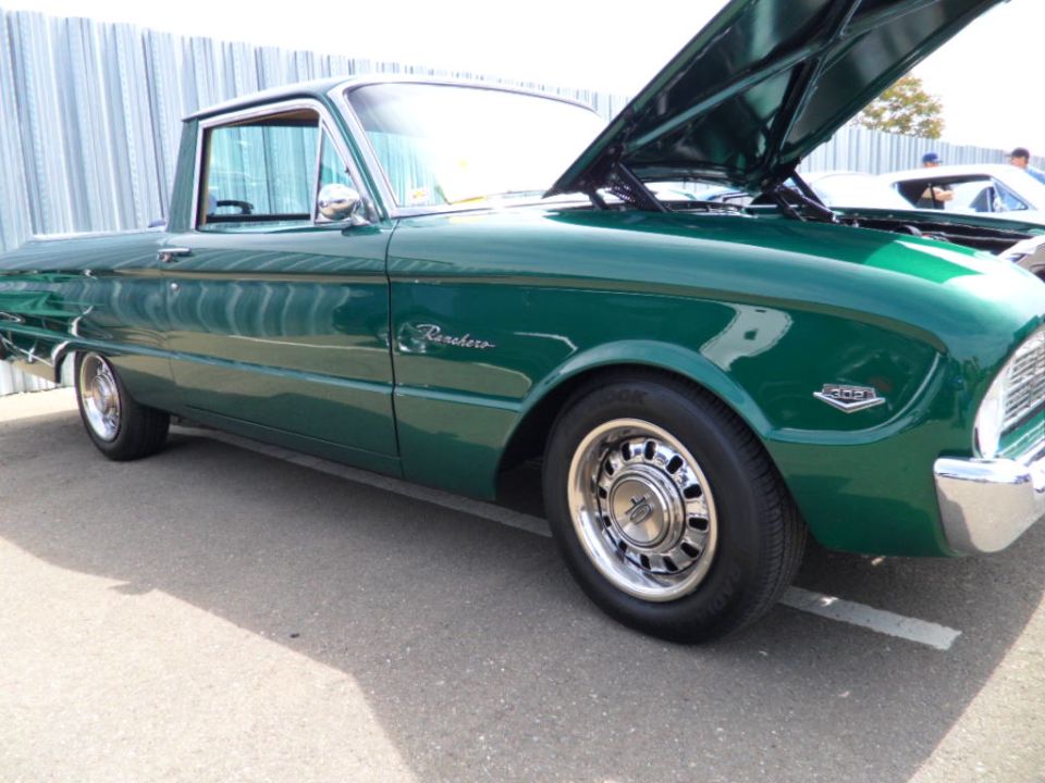 Green Ranchero pickup truck with hood open. Another car is parked behind it