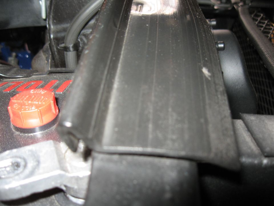 Close-up of engine bay with red cap and black plastic cover