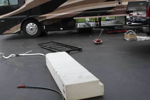 2003 Ford F-350 - An RV's side compartments are open, with a large white tank and other items on the ground.