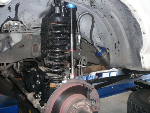 1988 Ford Bronco - This is a close-up view of the front suspension system of a vehicle, showing the shock absorber and coil spring assembly.
