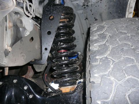 1988 Ford Bronco - Close-up view of a vehicle's suspension system, including a shock absorber and tire.