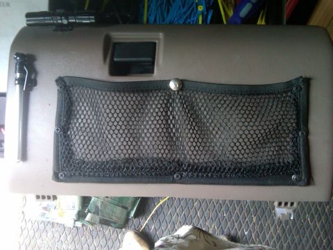 1993 Ford Bronco - A flashlight is attached to the interior door panel of a vehicle, which has a mesh storage pocket.
