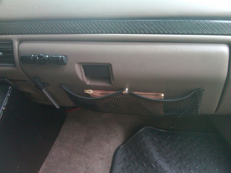 Interior dashboard with mesh organizer and a small bag. Supermotors.net logo visible