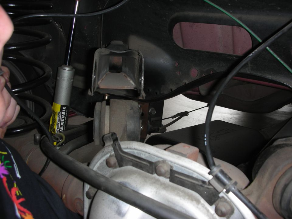 Underside view of rear leaf-spring shackle mount, shock absorber, and axle housing
