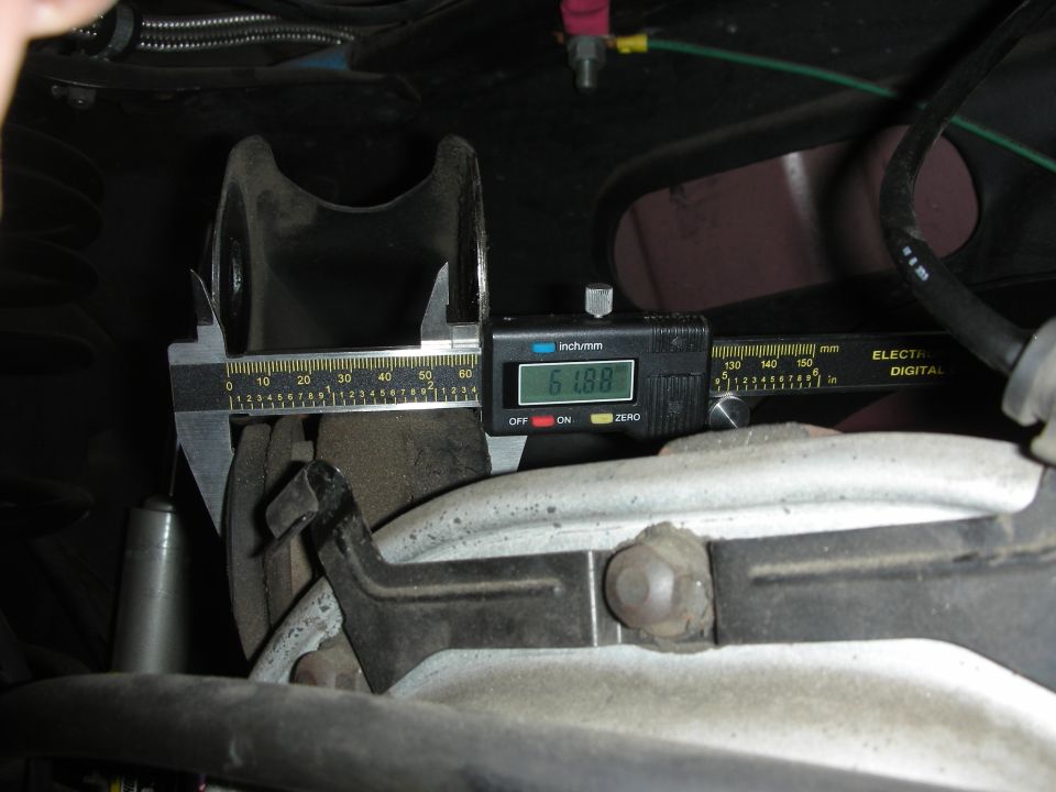 Digital caliper measuring a frame bracket under a vehicle