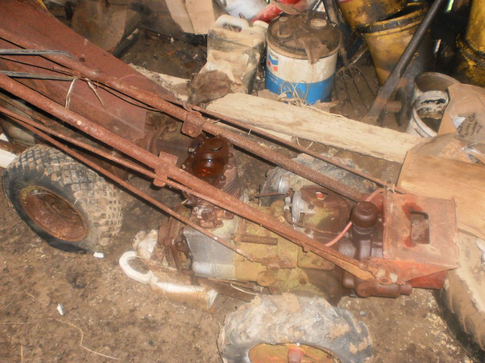 Rusty tiller with two wheels and engine visible, stored indoors