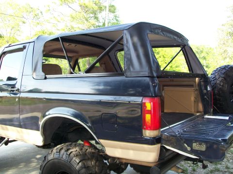 1990 Ford Bronco - This Ford Bronco has a removable soft top, revealing the interior and a spare tire mounted on the tailgate.