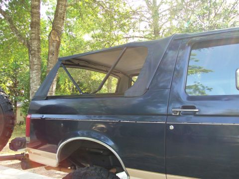 1990 Ford Bronco - Side view of a 1990 Ford Bronco with its soft top removed, revealing the interior roll cage structure.