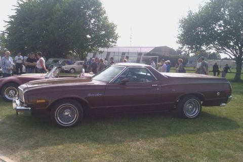1991 Ford Crown Victoria - A maroon 1977 Ford Ranchero is parked on grass at an outdoor car show with other vehicles and people in the background.