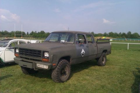 1991 Ford Crown Victoria - A four-door Dodge Ram pickup truck is parked on a grassy field next to a white car.
