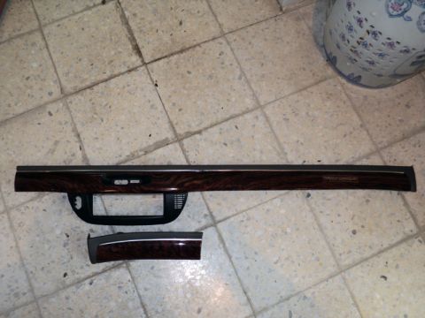 2001 Mercury Grand Marquis - Two wood-grain dashboard trim pieces are laid out on a tiled floor, likely for replacement.