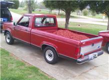 1995 Ford Bronco - A red Ford pickup truck is parked on a driveway, partially obscured by another vehicle.