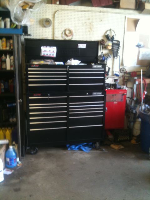1993 Ford Bronco - A large black tool chest is the main focus in this garage scene, with various tools and shelves visible in the background.