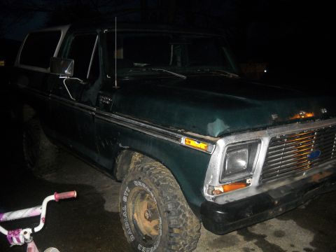 1993 Ford F-150 - This dark green Ford Bronco is parked outdoors at night, showing its front end and driver's side.