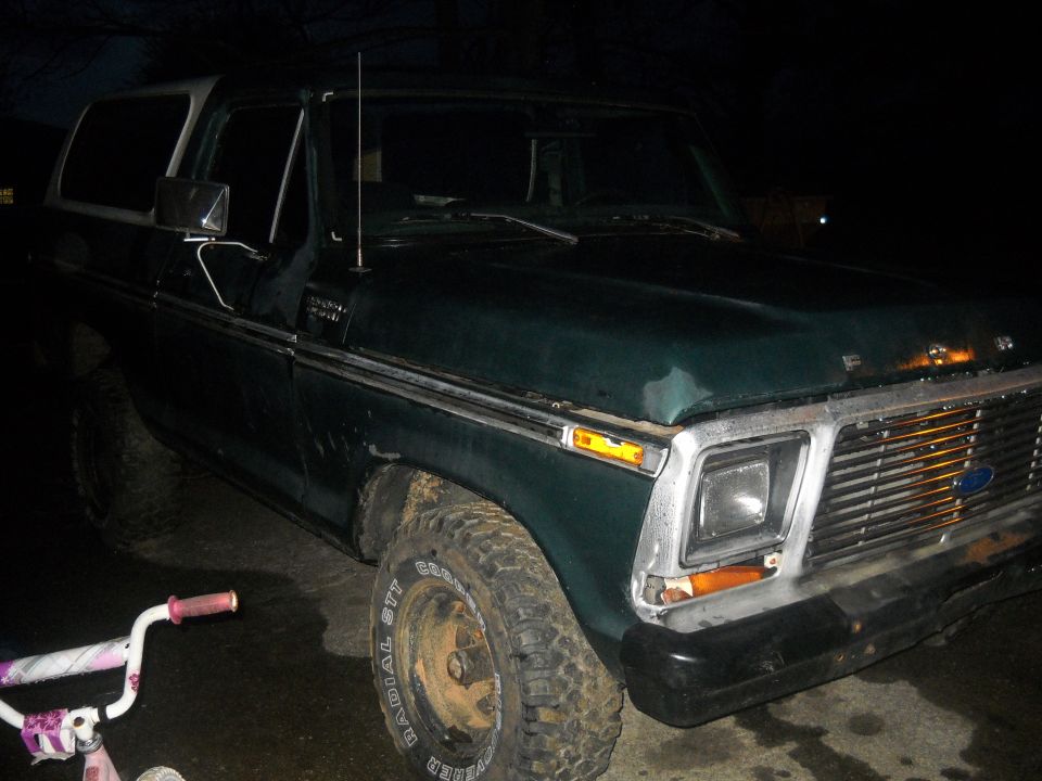 Green Ford Bronco with white top, front quarter view. Has a chrome grille and square headlights