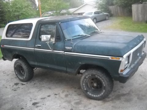 1993 Ford F-150 - This classic Ford Bronco features a two-tone paint scheme and off-road tires, parked on a concrete driveway.