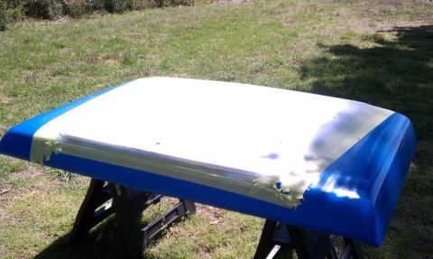 1979 Ford Bronco - A car roof panel is prepped for painting, resting on sawhorses outdoors.