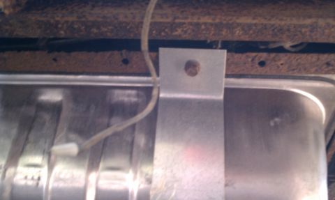 1979 Ford Bronco - This image shows the underside of a vehicle, focusing on the fuel tank and the rusted frame components.