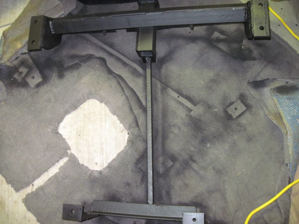 Painted metal frame with mounting brackets, laid on a floor with dark stains
