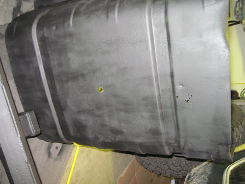 1979 Ford Bronco - The underside of a vehicle's fuel tank is shown, with a yellow wire visible beneath it.