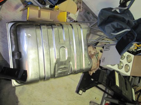 1979 Ford Bronco - A metal fuel tank with a ribbed surface is shown in a cluttered garage setting.