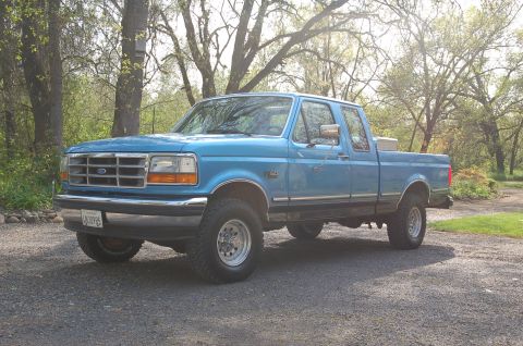 1992 Ford F-150 - This blue 1992 Ford F-150 pickup truck is viewed from a three-quarter front angle, parked outdoors.