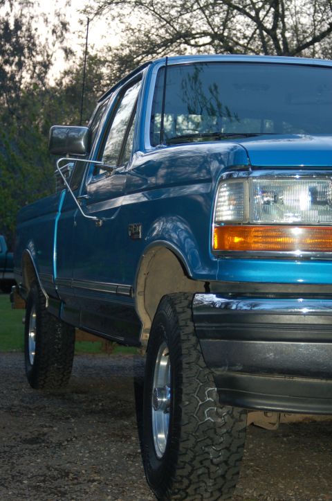 1992 Ford F-150 - A blue pickup truck is shown from the front quarter angle, parked outdoors on a gravel surface.