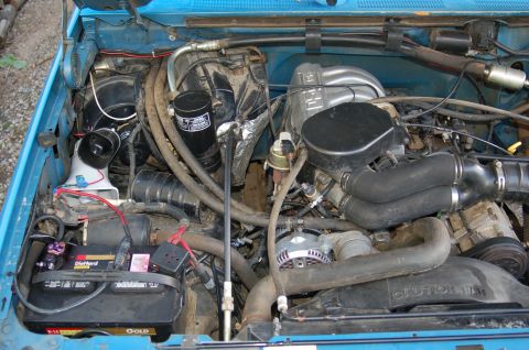 1992 Ford F-150 - Engine bay of a 1992 Ford F-150, showing the battery, alternator, and various engine components.