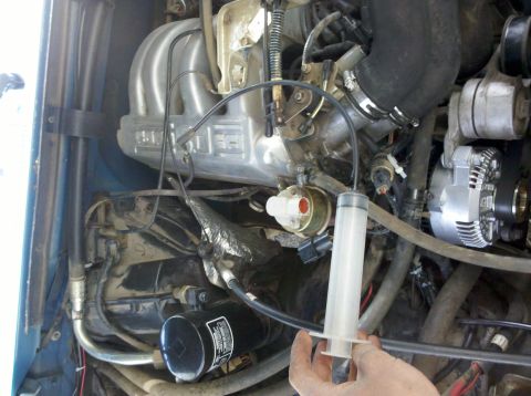 1992 Ford F-150 - A close-up view of the engine bay of a 1992 Ford F-150, showing various engine components and a syringe.