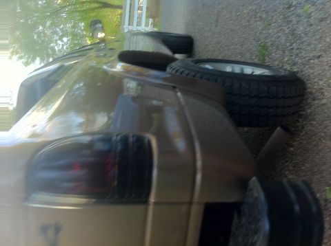 2001 Dodge Dakota - A spare tire rests on the bed of a pickup truck, seen from the rear corner.