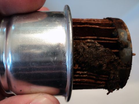 2001 Mercury Grand Marquis - A heavily clogged coolant filter shows significant buildup of dark, sludgy material on its pleated filter media.