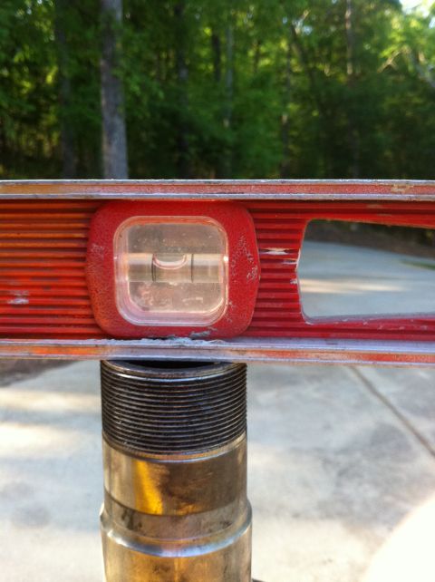 1996 Ford Bronco - A level tool is positioned over a metal threaded shaft, indicating a measurement or alignment task.