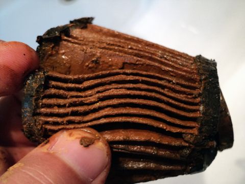 2001 Mercury Grand Marquis - A heavily clogged coolant filter shows extensive buildup of brown sludge and debris.
