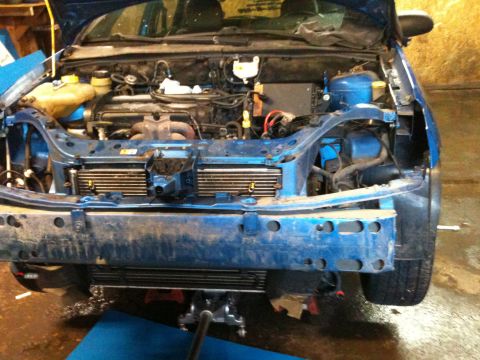 2002 Ford Focus - The front end of a blue 2002 Ford Focus is shown with the bumper removed, revealing the engine bay and radiator.