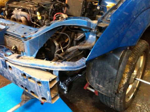 2002 Ford Focus - The front end of a blue car is disassembled, revealing the engine and supporting structures.