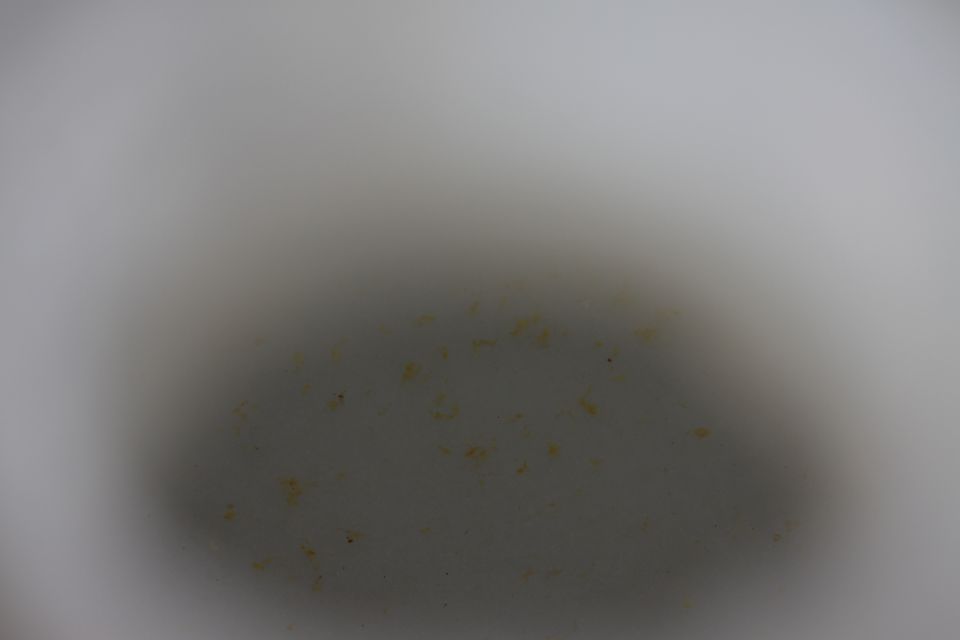 Close-up of a dirty, possibly metal, vehicle part with some yellow discoloration