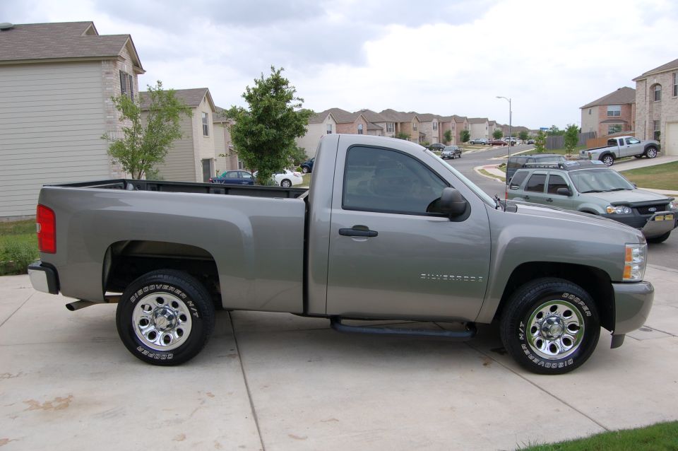 Silver pickup truck, side view, parked on driveway. "Silverado" text visible on door