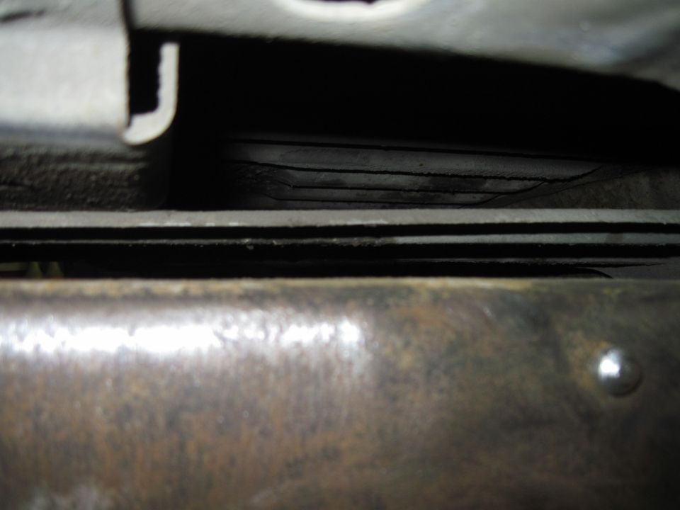 Close-up of layered metal parts underneath a vehicle, possibly frame rails