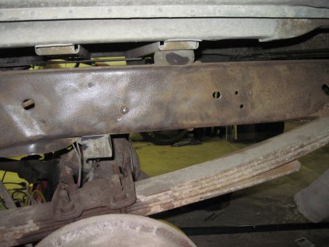 1979 Ford Bronco - Close-up view of the vehicle's undercarriage, highlighting the rusty frame and leaf spring suspension system.