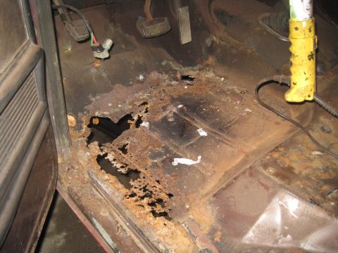 1979 Ford Bronco - The interior floor pan shows extensive rust damage with holes and corroded metal.