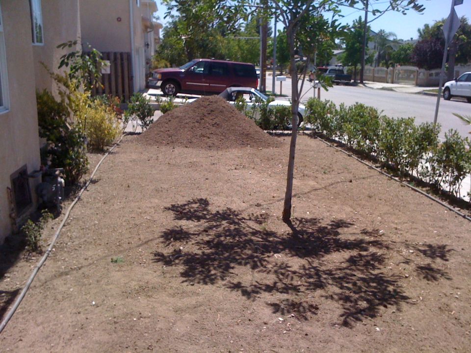 Red SUV and white convertible parked on street with pile of dirt in foreground